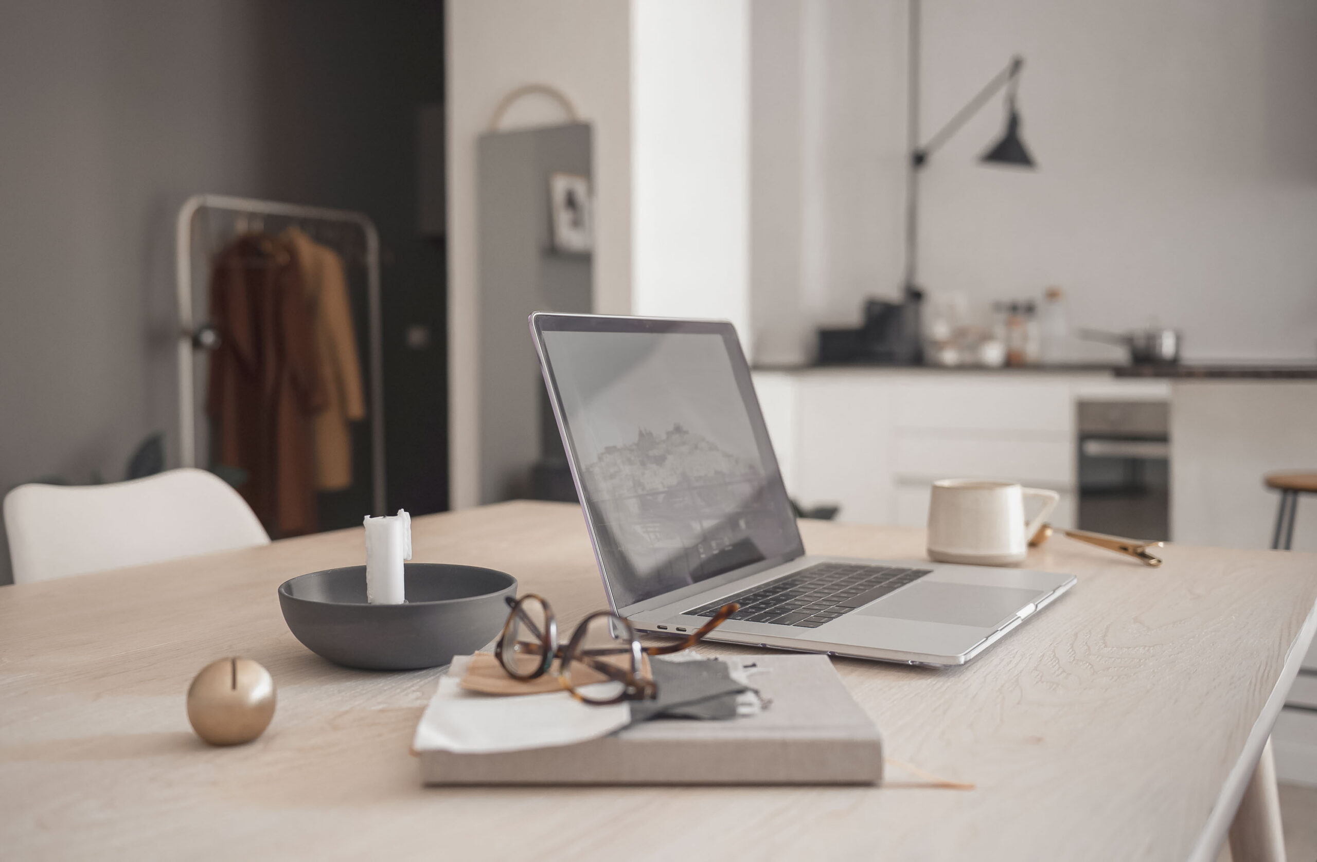 a laptop set at a kitchen table surrounded by work and home items