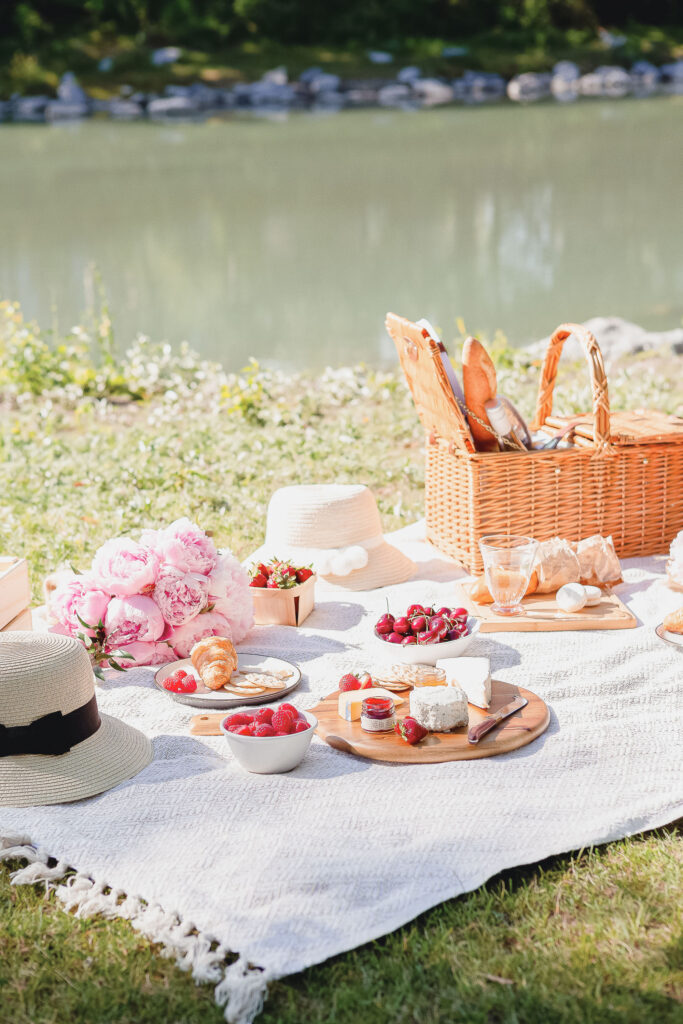 A sun-drenched picnic by the water with fruit, flowers, and food — a multi-sensory scene that illustrates how to boost creativity through everyday experiences