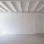 A blank white space with exposed beam ceiling, painted top to bottom in Pantone Color of the Year Cloud Dancer.