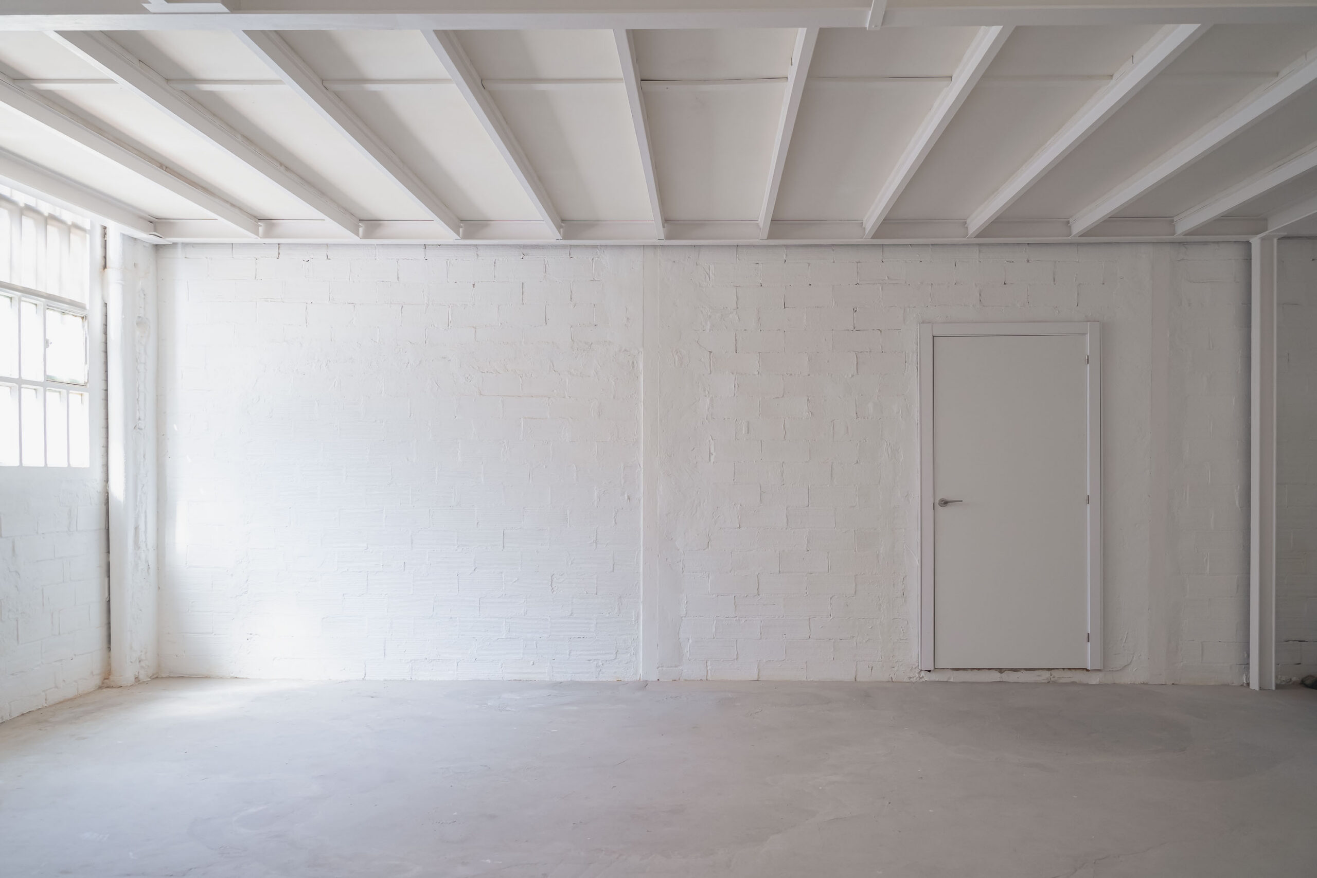 A blank white space with exposed beam ceiling, painted top to bottom in Pantone Color of the Year Cloud Dancer.