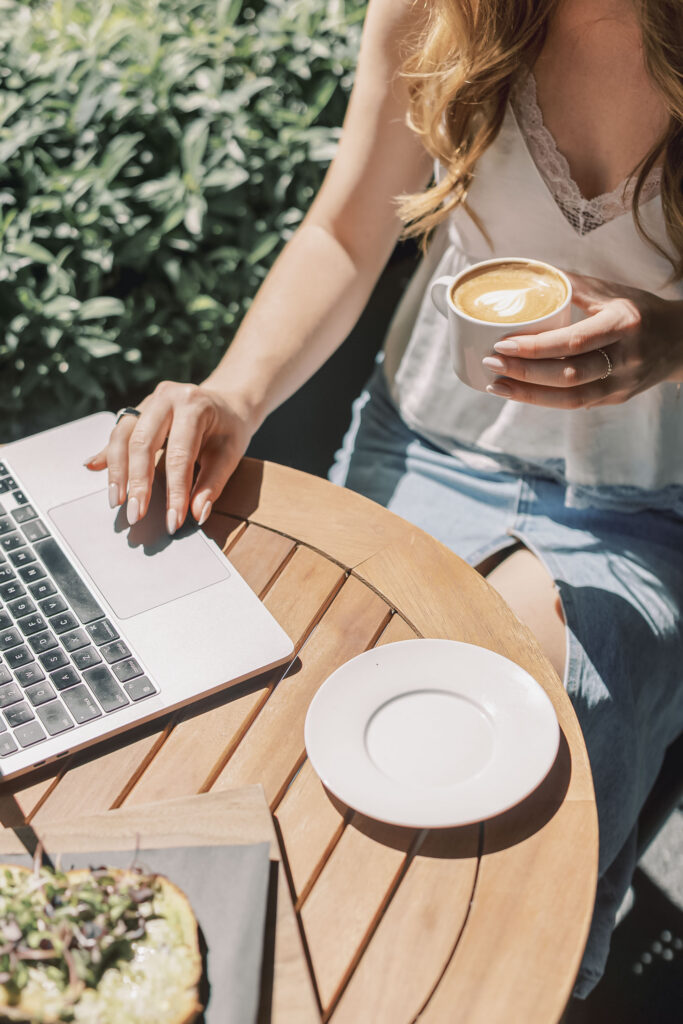 Sunlit outdoor café table with a laptop, latte and avocado toast — the kind of in-between moment where creative inspiration tends to surface.