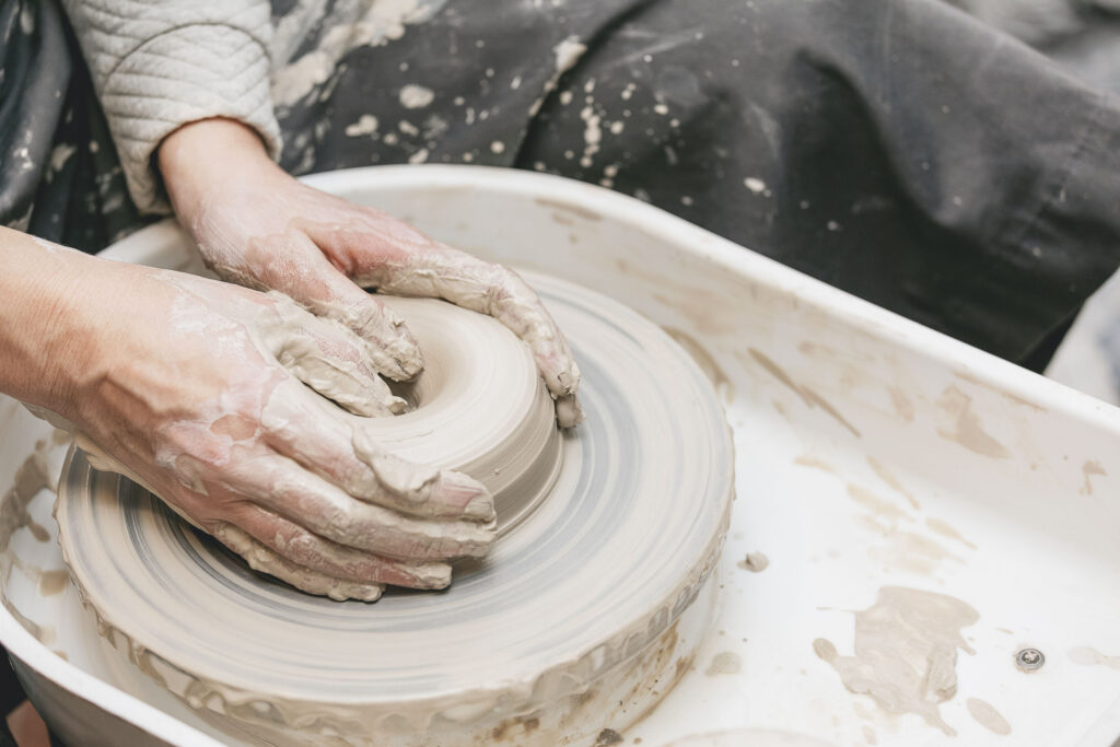 Hands shaping clay on a pottery wheel, illustrating how tactile creative work engages the sense of touch to boost creativity